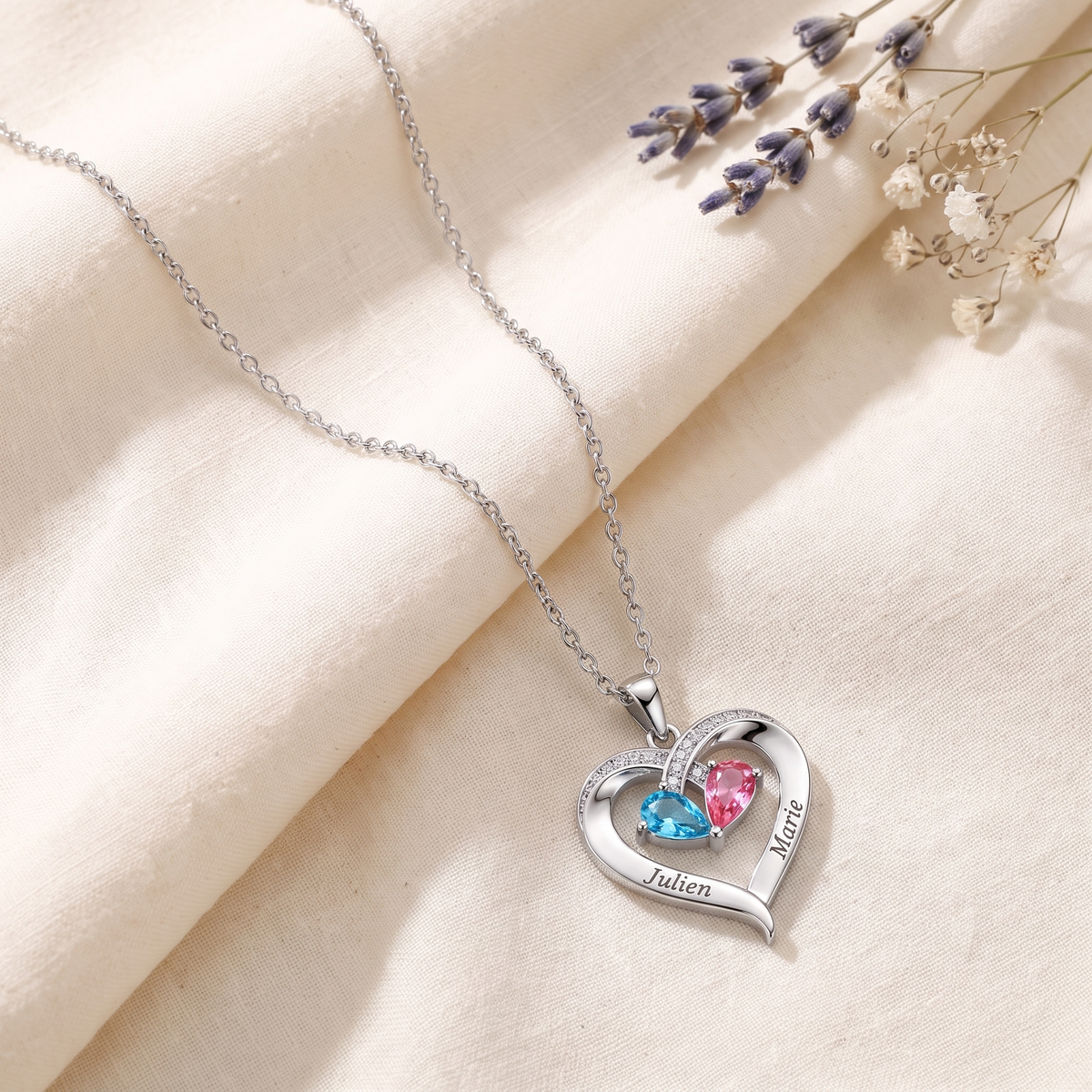 Collier cœur argenté posé à plat sur du lin