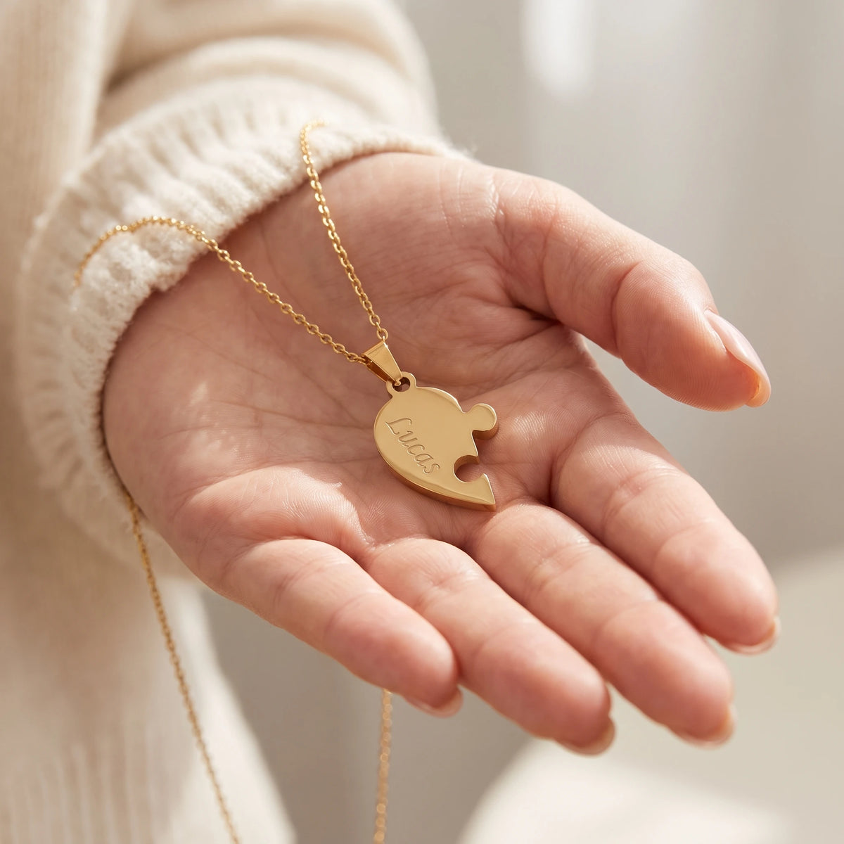Une pièce du collier Nous gravée d'un prénom, dans le creux de la main