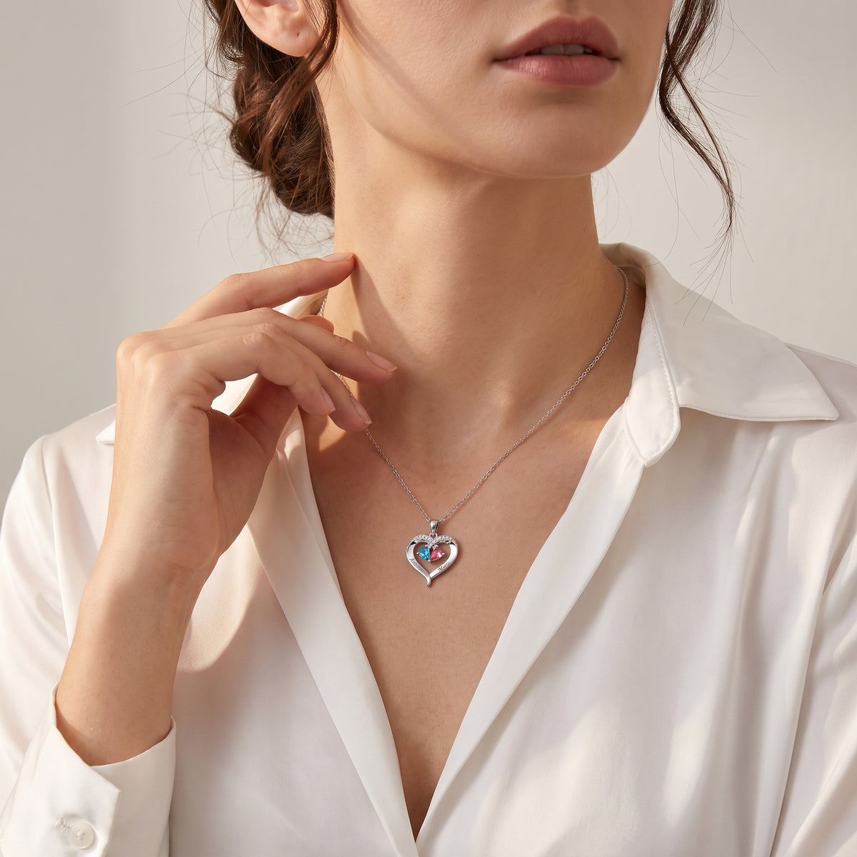 Femme portant le collier cœur argenté à deux pierres